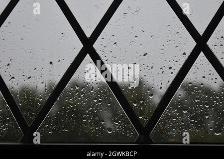 Gocce di pioggia su una finestra a forma di triangolo. Foto Stock