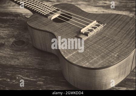 ukulele in legno in stile seppia su un tavolo Foto Stock