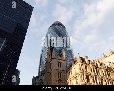 Londra, Greater London, Inghilterra, 21 2021 settembre: 30 grattacielo St Marys Axe, conosciuto anche come Gherkin, con la chiesa di St Andrew Undershaft. Foto Stock