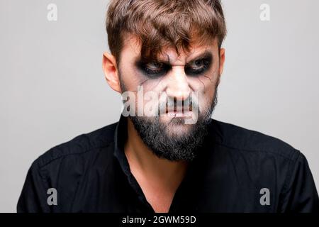 Ritratto di un uomo con una barba e un look minaccioso con un trucco in stile non morto il giorno di tutti i Santi del 31 ottobre Foto Stock