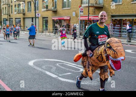 TOWER BRIDGE, LONDRA, INGHILTERRA - 03 ottobre 2021: Uomo che indossa un costume da dinosauro alla Maratona di Londra Virgin Money Foto Stock