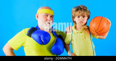 Nonno e nonno sportivi. Nipote con palla da basket e nonno con guanti da boxe. Sport per la famiglia. Foto Stock