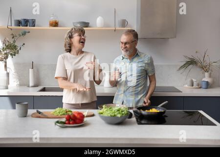 Spensierate le vecchie coppie di famiglia che ballano, preparando il cibo in cucina. Foto Stock