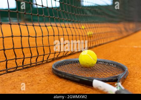 Palla da tennis e racket giacciono a terra vicino alla rete Foto Stock