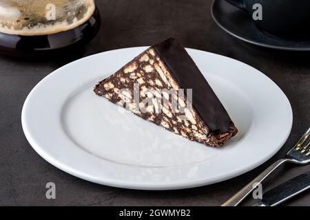 Torta a mosaico con cioccolato e biscotti su un tavolo di pietra nera Foto Stock