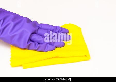 mano in un guanto viola con uno straccio giallo su sfondo bianco, primo piano Foto Stock