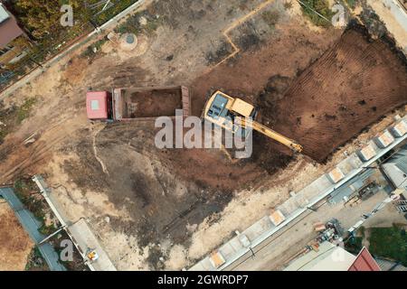 Scavo di fondazioni con escavatore in cantiere vista dall'alto aerea. Foto Stock