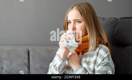 La giovane donna si ammalò di freddo. Donna in sciarpa con fazzoletto di nappino soffre di naso che cola e mal di gola e febbre. Stagionale freddo infettivo Foto Stock