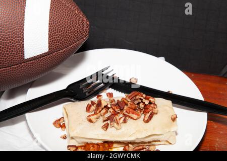 Calcio accanto ad un burrito coperto pecan e un tovagliolo Foto Stock