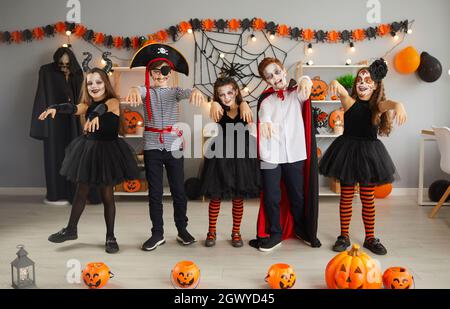 Gruppo di bambini in costumi spooky che ballano come zombie alla festa di Halloween a casa Foto Stock