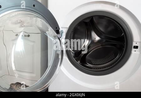 Cestello cromato di una lavatrice con coperchio aperto. Foto Stock