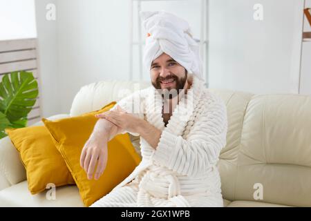 L'uomo bearded sfrega mano crema sulle sue mani. Spa, cura del corpo e della pelle per l'uomo concetto Foto Stock