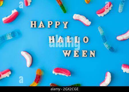 Concetto di Halloween. Halloween party decorazioni con parole Happy Halloween, dolci, vista dall'alto piatto su sfondo blu. Biglietto di auguri Foto Stock