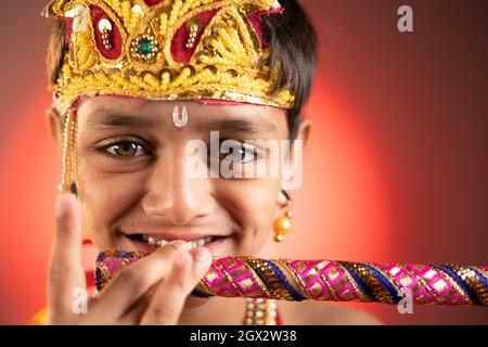 Primo piano colpo di capretto in costume di Lord krishna che suona flauto durante shri krishna Janmashtami. Foto Stock