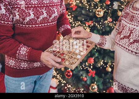 Coppia di ritratti di foto ritagliati che decorano l'albero di Natale con baubles festive indossando maglioni Foto Stock