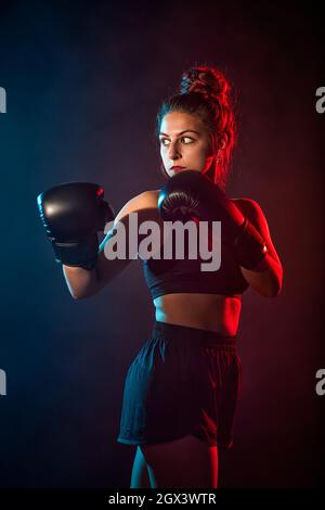 Donna sportiva che fa esercizi di boxe, facendo colpo diretto. Foto della giovane ragazza. Forza e motivazione. Foto Stock