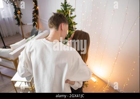 Vista sul retro di una bella giovane coppia che abbraccia. Festa di Natale Foto Stock