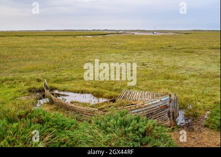 Il relitto erodente di una barca di legno posata per riposare sulla palude della Riserva Naturale Naturale di Blakeney, Norfolk, Inghilterra. Foto Stock