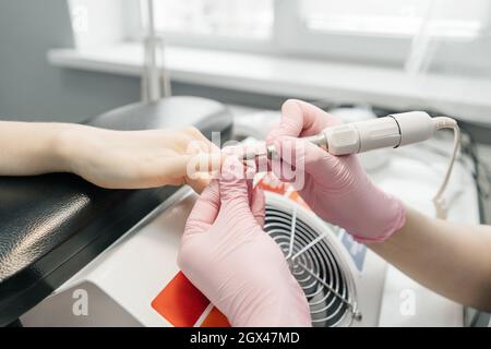 Processo di rimozione manicure in salone di bellezza. Il manicurista nei guanti rimuove il vecchio manicure. Primo piano con le mani. Foto Stock