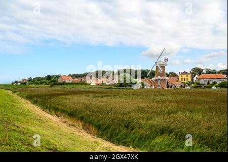 Cley sul mare villaggio con il suo mulino a vento visto da un sentiero pubblico argine su Blakeney Freshes, Norfolk, Inghilterra. Foto Stock