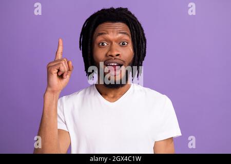 Foto di giovane felice pelle scura allegro uomo punto dito su idea soluzione isolato su sfondo di colore viola Foto Stock