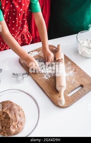 vista croppata della ragazza afro-americana che taglia l'impasto con taglierina per biscotti a forma di testa di renna Foto Stock