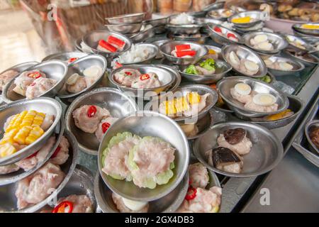 Una serie di gnocchi Dim Sum Streamer serviti su piccoli piatti di acciaio inossidabile in un ristorante cinese-tailandese locale a Betong, Yala, Thailandia. Foto Stock