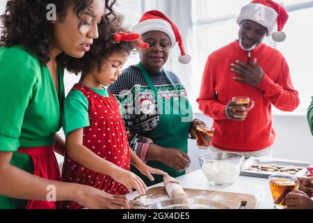 felici i nonni afroamericani che guardano la nonna che prepara i biscotti di natale con la madre Foto Stock