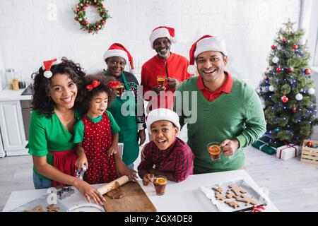 le donne afroamericane si stendono la pasta mentre preparano i biscotti di natale con la famiglia Foto Stock
