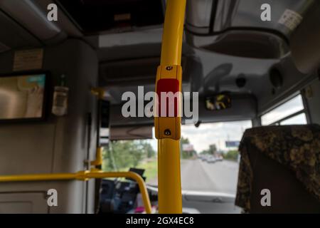Pulsante per la comunicazione con il conducente sul supporto del corrimano nell'abitacolo dell'autobus pubblico cittadino. Foto Stock