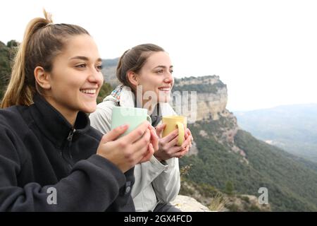 Due escursionisti felici bere caffè e contemplare in una scogliera Foto Stock