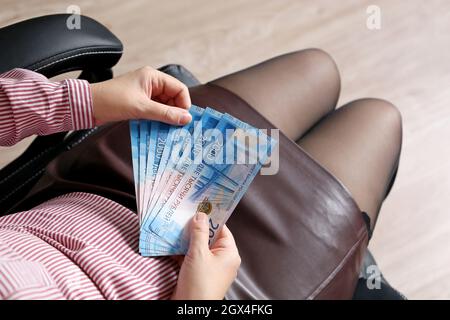 Rubli russi in mani femminili, pagamento in contanti, stipendio o concetto di tangente. Donna in ufficio vestiti seduti in sedia con carta valuta della Russia Foto Stock