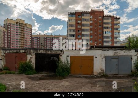 I garage sono in fila in una zona residenziale in un giorno d'estate, uno di loro ha un'iscrizione in russo - vendere. Foto Stock