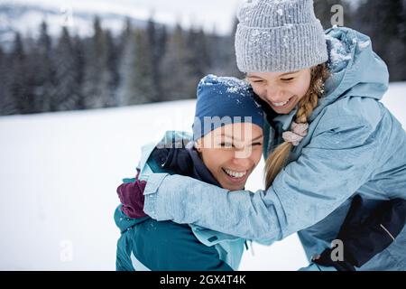 Madre con una bambina che si diverte all'aria aperta nella natura invernale. Foto Stock