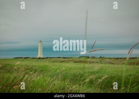 Vista panoramica del faro di Malarrif a est dell'islanda in una giornata nuvolosa. Alto faro in islanda di colore grigio e nuvole spesse sopra. Foto Stock