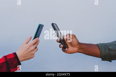 Primo piano di giovani coppie biraciali utilizzando smartphone su sfondo bianco Foto Stock