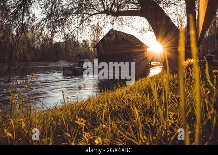 Bellissimo vecchio mulino in legno sul fiume Mura o Mlin na muri nella regione di pomurje in slovenia in un romantico tramonto estivo Foto Stock