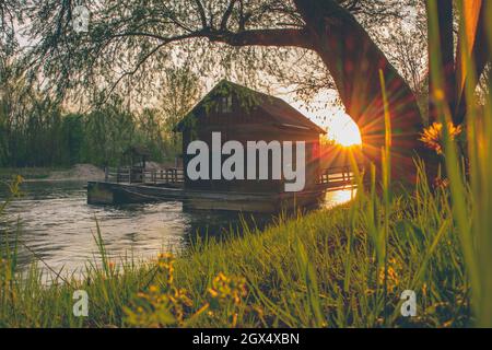 Bellissimo vecchio mulino in legno sul fiume Mura o Mlin na muri nella regione di pomurje in slovenia in un romantico tramonto estivo Foto Stock