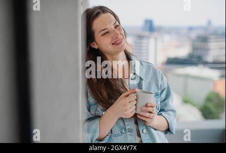 Ritratto di giovane donna caucasica con caffè all'aperto sul balcone Foto Stock