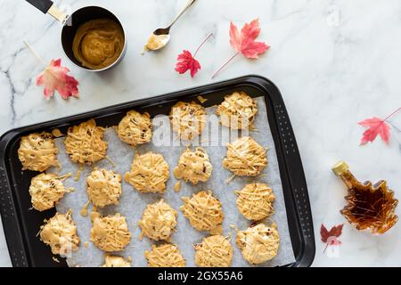 Vista dall'alto di un foglio di biscotti riempiti con biscotti di acero pecan gocciolato con glassa di acero. Foto Stock