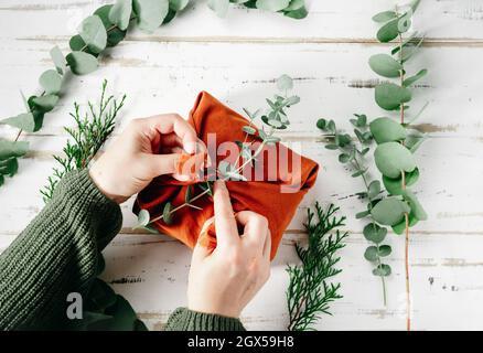 Confezionare un regalo in un tessuto ecologico riutilizzabile, furoshiki Foto Stock