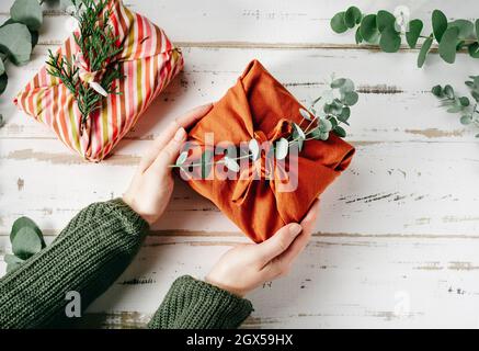Confezionare un regalo in un tessuto ecologico riutilizzabile, furoshiki Foto Stock