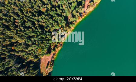 Vista aerea dall'alto verso il basso del drone della caduta sul lago vulcanico di Sant'Anna (Sfanta Ana). Foresta e acqua. Harghita, Romania, in autunno Foto Stock