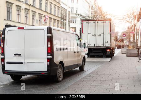 Piccolo furgone bianco e cargo di medie dimensioni parcheggiato per lo scarico sulla strada della città vecchia europea. Concetto di servizio di consegna rapida del corriere espresso. In movimento Foto Stock
