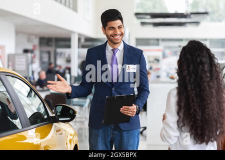Signora mediorientale che sceglie la nuova automobile, avendo colloquio con il responsabile vendite Foto Stock