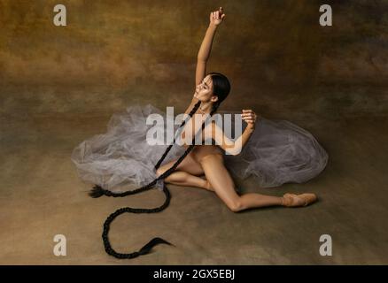 Ritratto mozzafiato di ballerina femminile bella ballerina, ballerina tenera in posa su elemento di tessuto trasparente isolato su sfondo studio Foto Stock