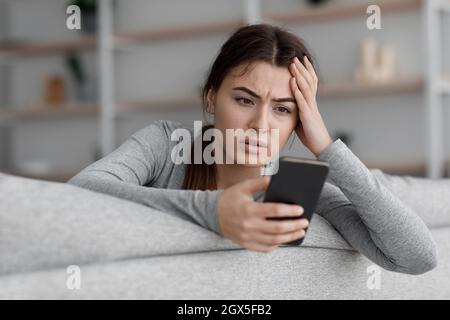 Triste frustrato scioccante giovane europea che soffre di depressione e che legge il messaggio con cattive notizie Foto Stock