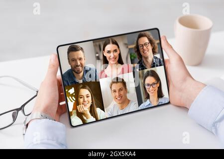 Il giovane ragazzo caucasico utilizza il tablet per effettuare chiamate online con il colpo di testa delle persone, comunicando in remoto sul posto di lavoro Foto Stock