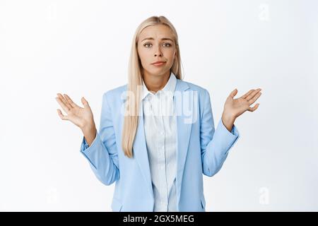 Indecisa donna d'affari che si rugge con mani vuote, niente da dire, non so, in piedi senza indizio su sfondo bianco Foto Stock