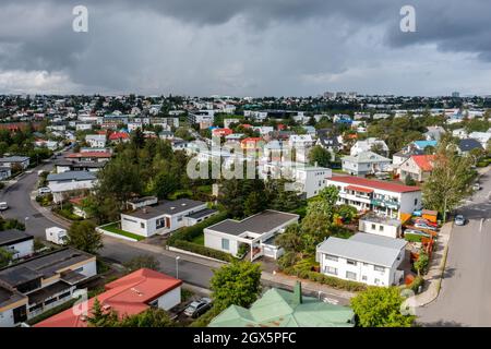 Vista aerea di case suburbane e alberi verdi situato vicino asfalto strada contro cielo nuvoloso in noioso giorno d'estate in città. Foto Stock